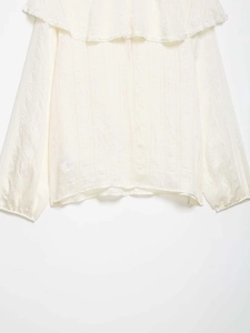 Détail du col volanté avec bordure en dentelle et texture rayée sur une chemise beige