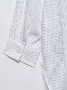 Close-up of pinstripe shirt sleeve cuff showing fabric texture and resin button detail