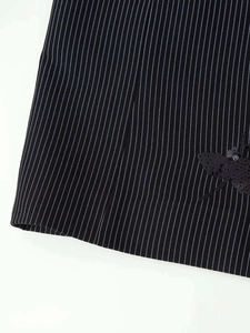 Close-up of black and white pinstripe fabric with detailed black sequin bee embroidery