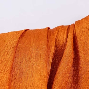 Close-up of bright orange pleated fabric texture on a sleeveless summer vest top