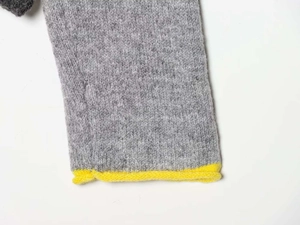 Detailed close-up of grey knit sweater cuff with vibrant yellow rolled edge finish