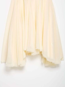Detail of light yellow pleated dress hem featuring delicate frayed edge craftsmanship