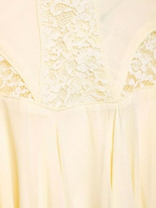 Detailed close-up of cream chiffon dress with white lace trim and vertical pleats