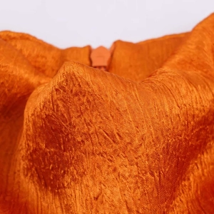 Detailed macro view of vibrant orange crinkled fabric texture with matching zipper closure