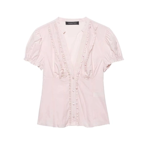 Detail of light pink V-neck shirt with delicate ruffle trim and puffed short sleeves