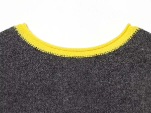 Detail of the dark gray knit texture and yellow ribbed crew neck stitching on the sweater