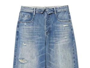 Detail of high-waisted light blue washed denim jeans with distressed ripped edges