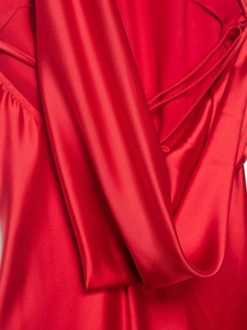 Detail of red satin dress featuring luxurious silk-like texture and delicate halter neck ties