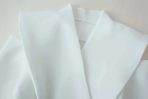 Detail view of a white off-shoulder blazer jacket showing fabric texture and lapel design