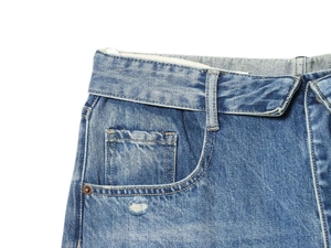 Detailed close-up of blue denim jeans with stone wash finish and copper rivets
