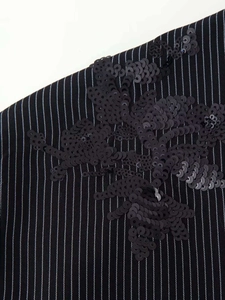 Detailed embroidery of black sequins in floral patterns on striped fabric