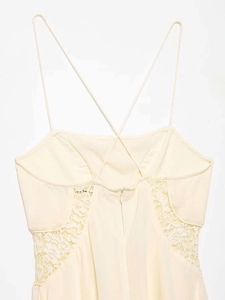 Detail of cross straps and delicate floral lace on a sleeveless summer dress