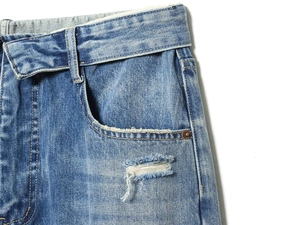 Close-up of light blue jeans waist with heavy wash effect and distressed pocket detail