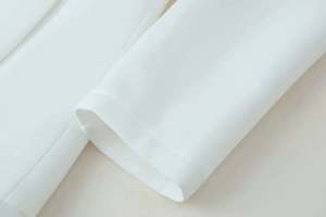 Close-up of clean stitching and high-quality white fabric on a women's blazer sleeve