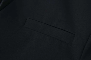 Detailed close-up of a neat welt pocket on a black V-neck long-sleeve blazer jacket