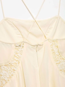 Detail of cream summer dress featuring thin cross straps, hidden zipper and lace panels
