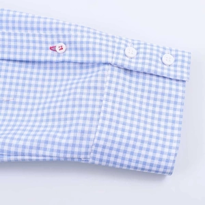 Detail of gingham shirt cuff with white buttons and unique red contrast stitching accent