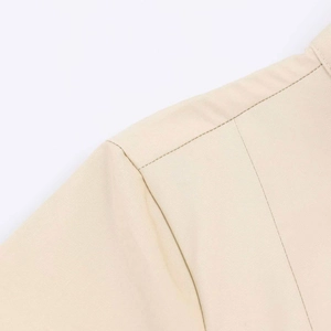 Detailed macro view of high-quality shoulder stitching and twill fabric on a beige dress