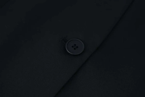 Close-up of black single-breasted blazer with four-hole round buttons and woven texture