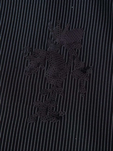 Macro shot of black sequin floral embroidery on a pinstriped fabric detail for suits