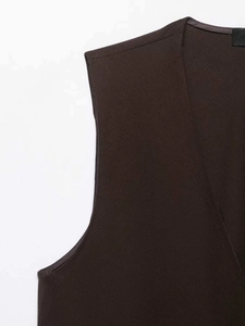 Close-up of the V-neckline and textured dark brown fabric of a tailored vest