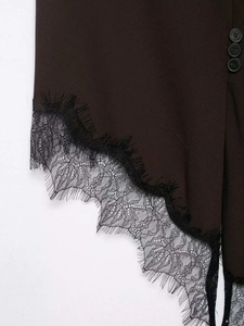 Detail of dark brown asymmetric hem featuring black eyelash lace and button accents