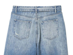 Detail of vintage washed blue denim jeans showing back pockets and distressed worn edges