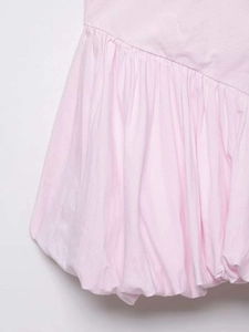 Dettaglio di un abito in popeline rosa con cuciture diagonali e orlo a palloncino plissettato