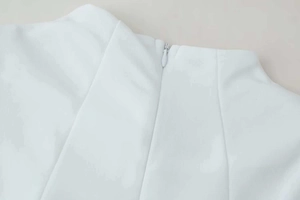 Vue détaillée d'une robe blanche montrant une fermeture éclair invisible sur tissu tissé