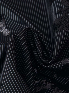 Detail of black fabric with vertical stripes and intricate black floral sequin embroidery