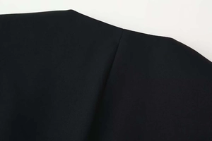 Detailed close-up showing the smooth black fabric texture and neat seams of the V-neck jacket