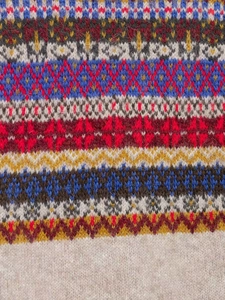 Macro detail of Fair Isle geometric knit pattern in blue, red, and yellow wool blend fabric
