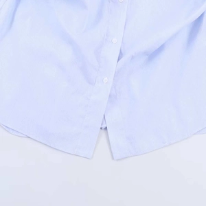 Detail view of light blue striped shirt featuring white buttons and a curved hemline