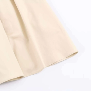 Detailed close-up showing the neat hem and fine stitching of the apricot dress fabric