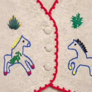 Knitted beige vest featuring red crochet edges and blue horse embroidery detailing