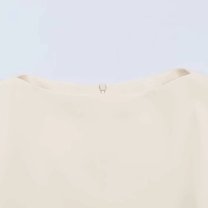 Détail macro du col bardot blanc cassé avec boucle métallique argentée sur le chemisier