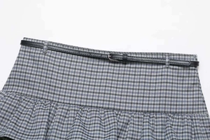 Detail of grey-blue plaid pleated skirt featuring a slim black leather belt and silver buckle