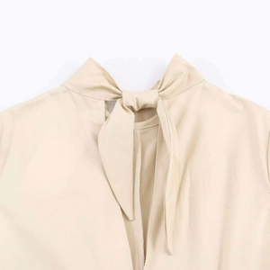 Detail view of beige dress featuring back neck tie bow and vertical slit design