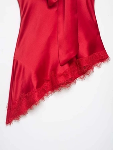 Detail of red satin fabric featuring delicate lace trim and asymmetrical hem design