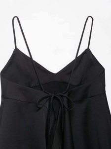 Detail of minimalist black V-neck top showing cross-back lace-up ties and thin straps