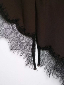 Detailed close-up of dark brown fabric with exquisite black eyelash lace trim floral edge