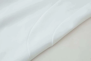 Gros plan sur le tissu tissé blanc avec un ourlet incurvé et des coutures doubles