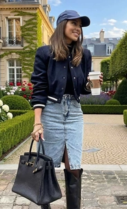 Detail of dark blue cropped varsity jacket paired with a split denim midi skirt
