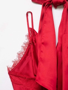 Detail view of red satin top with delicate eyelash lace trim and silk bow neck tie