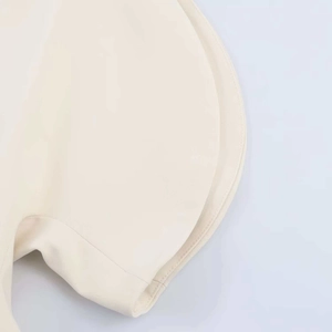 Détail de la blouse blanc cassé à épaules dénudées avec coutures fines et volants aux manches