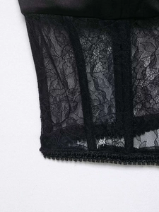 Detail eines schwarzen Satintops mit transparenten Blumenspitzen-Einsätzen und Stäbchen