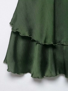 Close-up of dark green mini skirt showing layered chiffon fabric and pleated texture