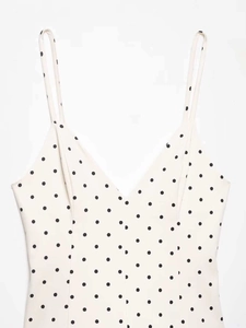 Detail of white V-neck dress featuring black polka dots and delicate thin straps