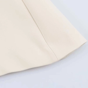 Gros plan sur la texture tissée ivoire et les coutures soignées du haut à épaules nues