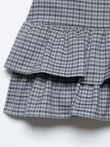 Detailed view of the double-layered ruffled hem and classic small plaid pattern on the skirt